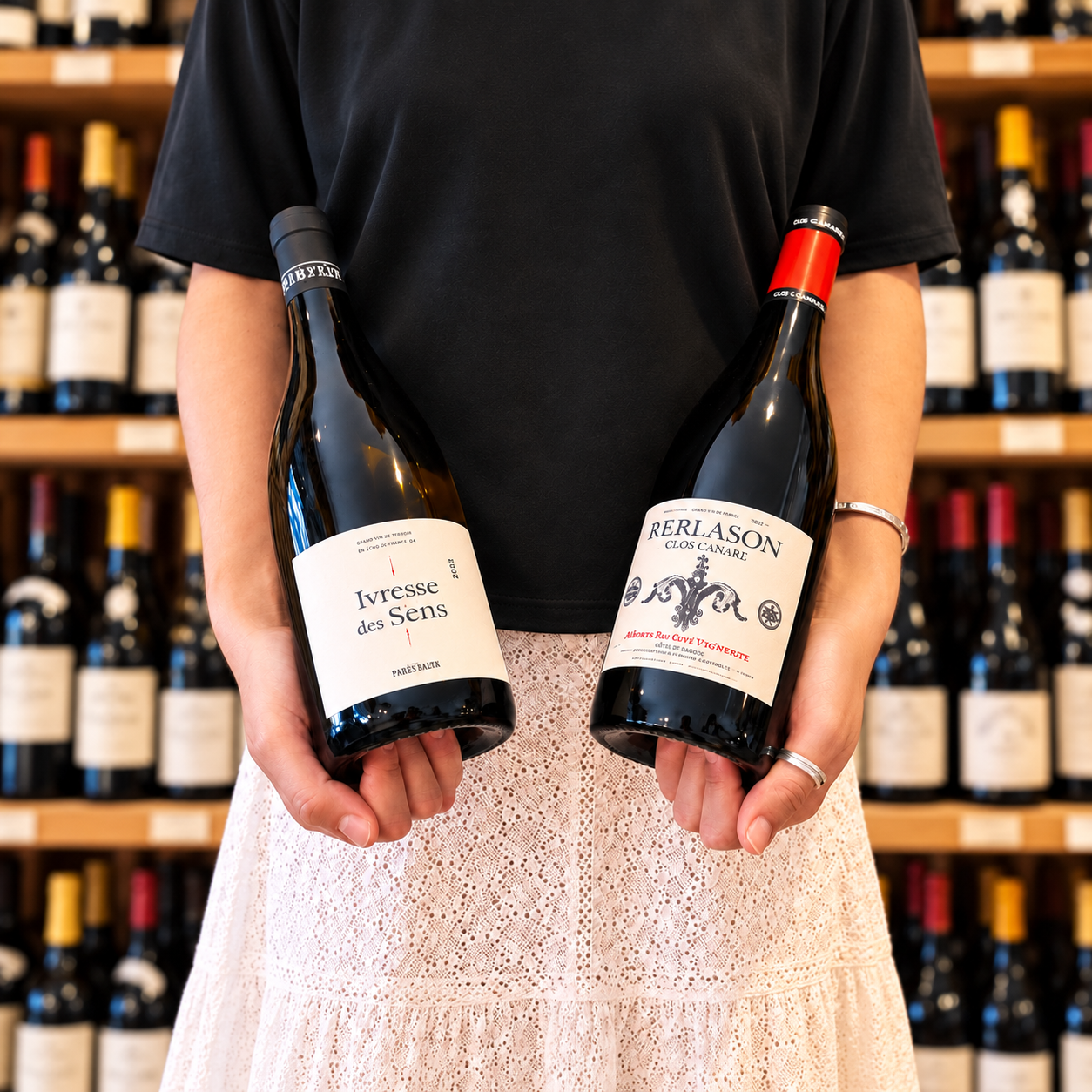 Personne tenant deux bouteilles de vin bio devant une cave à vin, pour illustrer l’Oenobox 100 % BIO d’Oenofeel.